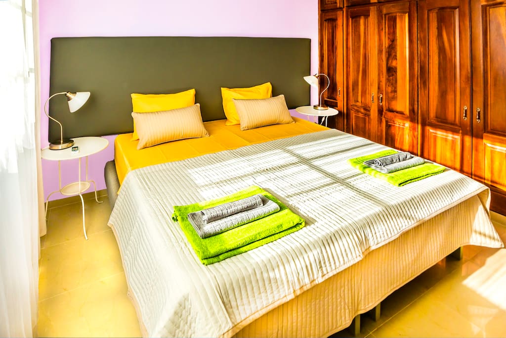 Lilac bedroom. Comfortable, super king size bed: 200cm x 200 cm, fresh linen. A kit of fresh towels. Here you can sleep well and enjoy your stay. Every room has a spacious closet so you can store your things. Lamps, ceiling fan, and air conditioner in every room will make your stay comfortable and enjoyable.